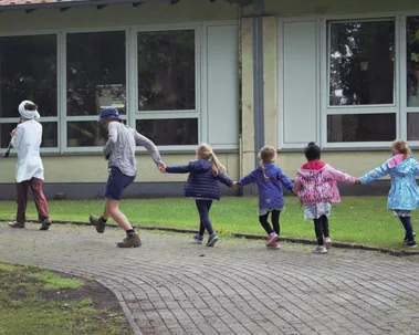 Kinder laufen Musikerin mit Klarinette in einer Reihe hinterher
