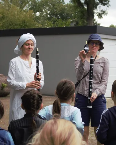 Musikerin und Musikvermittlerin zeigen Kindern eine Klarinette